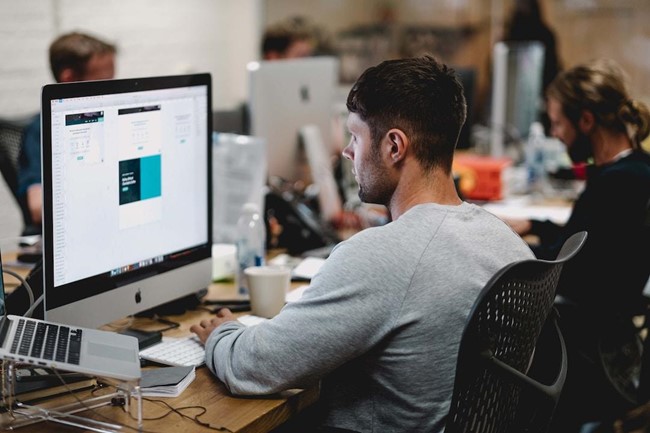 A man in an office researching RFP management on his computer